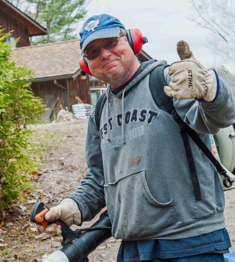 man-wearing-protective-head-gear-and-using-a-leaf-blower-gives-thumbs-up